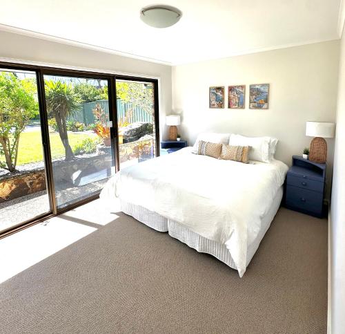 a bedroom with a white bed and a large window at Waterfront Retreat Mooloolaba in Mooloolaba