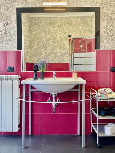 a bathroom with a white sink and pink walls at Bnbook Residence La Red in Rho