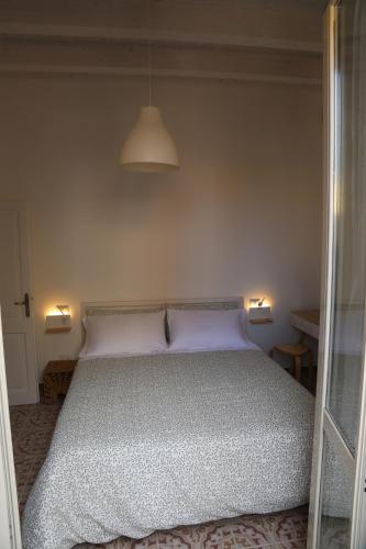 a bed in a bedroom with two lights on the wall at Casetta Amati 2 in Nettuno