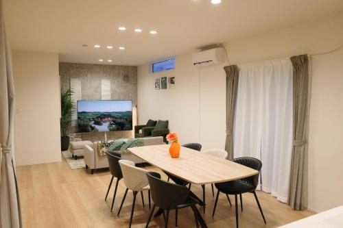 a living room with a table and chairs and a couch at 新築貸し切り宿 Karatsu House B in Karatsu