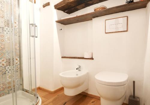 a white bathroom with a toilet and a shower at S'Ispera B&B, Home Restaurant, Autentiche Esperienze Sarde in Fonni