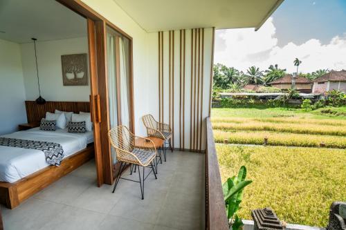 a bedroom with a bed and chairs on a balcony at Kemari Ubud in Ubud