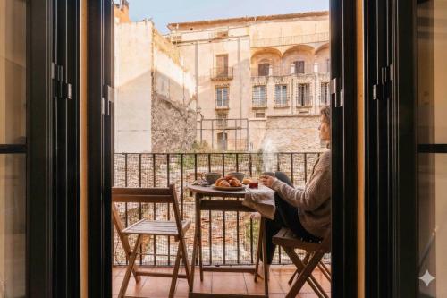 a woman sitting at a table with a plate of food at weroomies - Sant Domenec in Tarragona