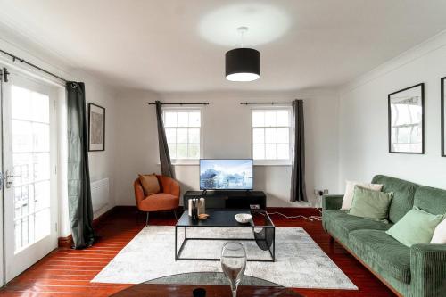 a living room with a green couch and a table at Bright 1 Bed Harbour-side Apartment with Balcony in Whitehaven