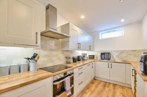 a kitchen with white cabinets and wooden counter tops at Host & Stay - Llanberis Flat in Llanberis