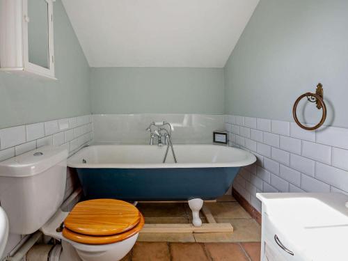 a bathroom with a blue tub with a toilet and a sink at 3 Bed in Tywyn oc-dy021 in Tywyn