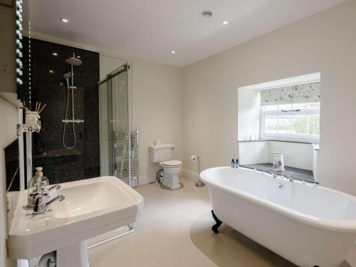 a white bathroom with a tub and a sink at 1 Bed in Bideford oc-51784 in Parkham
