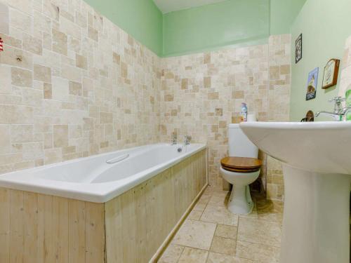 a bathroom with a tub and a toilet and a sink at 3 Bed in Braunton oc-86704 in Braunton