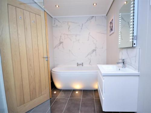 a bathroom with a white tub and a sink at 1 Bed in Conwy oc-60294 in Llangelynin