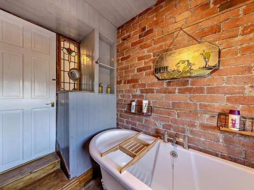 a bath tub in a room with a brick wall at 4 Bed in Bala oc-94665 in Bala