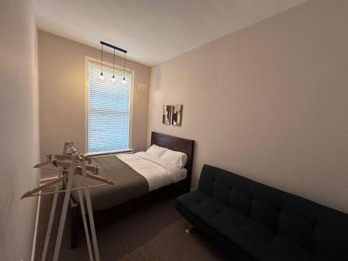 a bedroom with a bed and a couch and a window at Spacious Victorian Apt Sleeps 5 Parking available in Nottingham