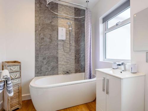 a white bathroom with a tub and a sink at 4 Bed in Llandudno oc-75466 in Llandudno