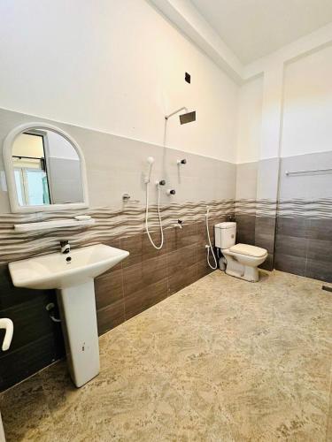 a bathroom with a sink and a toilet at Surf Bay Hotel in Arugam Bay