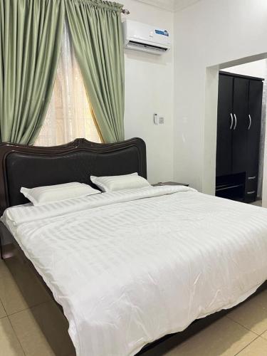 a bedroom with a bed with white sheets and a window at Shana Homes in Karsana