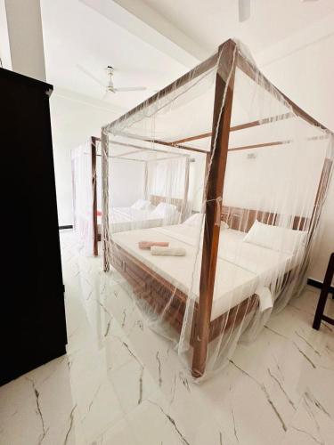 a bedroom with a bed covered in mosquito net at Surf Bay Hotel in Arugam Bay