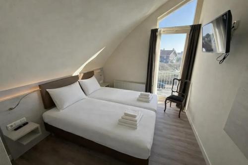 ein weißes Bett in einem Zimmer mit Fenster in der Unterkunft Hotel Rasch in Bergen aan Zee