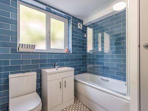 a blue tiled bathroom with a toilet and a bath tub at 3 Bed in Brixham oc-88116 in Brixham