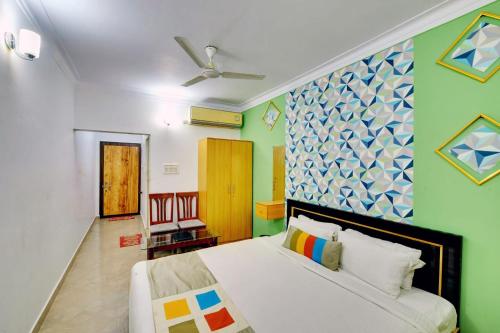 a bedroom with a white bed and a green wall at Royal Garden Brindavan Resort in Hosa Kannambādi
