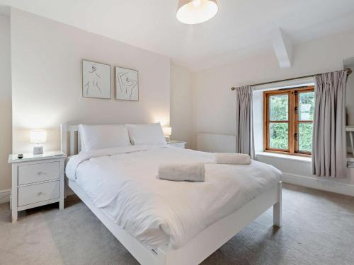a white bedroom with a large white bed and a window at 4 Bed in Ilfracombe oc-95899 in Berrynarbor