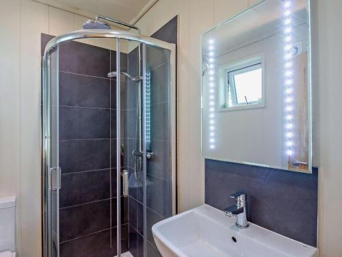 a bathroom with a shower and a sink and a mirror at 2 Bed in Conwy oc-50284 in Llangelynin