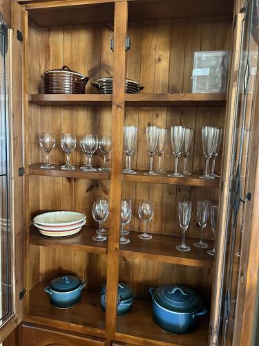 a wooden cabinet with glasses and plates and dishes at Cosy Heritage Cottage in Ararat