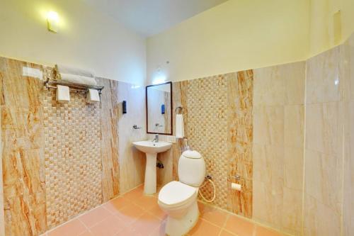 a bathroom with a toilet and a sink at Royal Garden Brindavan Resort in Hosa Kannambādi