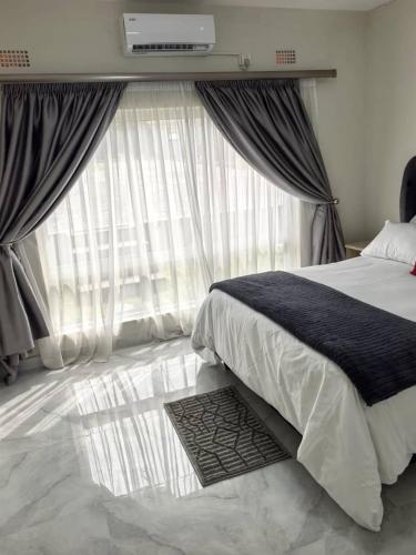 a bedroom with a bed and a large window at Nkambo Apartments in Kitwe