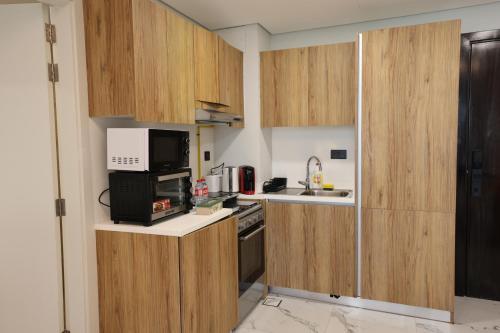 a small kitchen with wooden cabinets and a microwave at Maryah Island Luxe 1 Bed Junior by Central Stay in Abu Dhabi