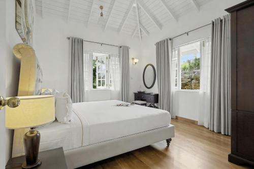 a white bedroom with a bed and two windows at Aadya Tea Bungalows by Aahaasa in Hatton