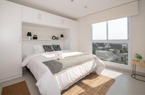 a white bedroom with a large bed with two teddy bears on it at Cityscape Views - New 2BR Retreat in Asunción
