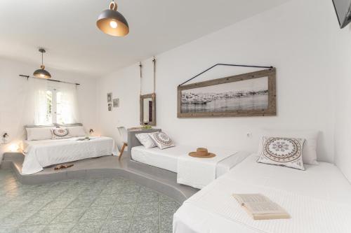 a white living room with two beds and a couch at Palatiana Agriturismo-Philoxenia Cottages Retreat in Galini