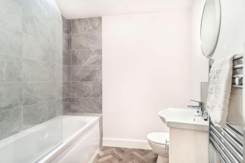 a bathroom with a tub and a toilet and a sink at Smart 1 Bed Apartment in Central Wrexham in Wrexham