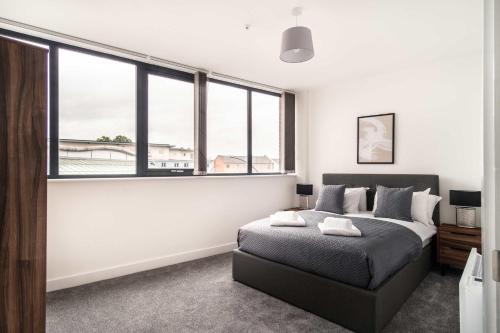 a bedroom with a bed and large windows at Smart 1 Bed Apartment in Central Wrexham in Wrexham