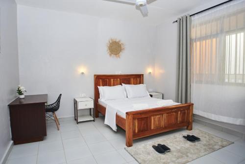 a bedroom with a bed and a desk and a window at Diani Dream stays 2 in Diani Beach