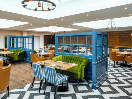 a restaurant with a green couch and tables and chairs at Mercure Oxford Hawkwell House Hotel in Oxford