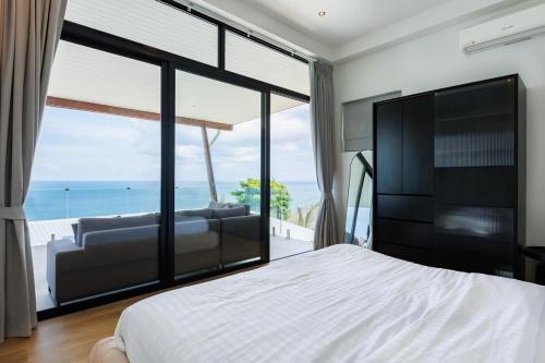 a bedroom with a bed and a view of the ocean at Shamgrila - Panoramic Sea View in Ko Phangan