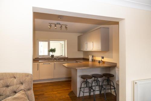 a kitchen with white cabinets and bar stools at Bay Apartment 1 in Morecambe
