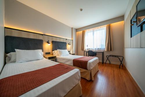a hotel room with two beds and a window at Posadas de España Pinto in Pinto