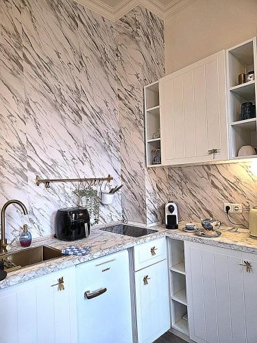 a kitchen with white cabinets and a marble wall at Midcoast Studio TheBlue in Nortorf