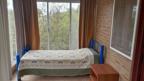 a bedroom with a bed in front of a window at Cuesta Blanca cabañas in Cuesta Blanca