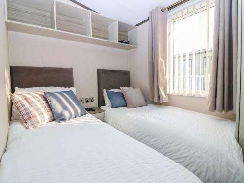 two beds in a small room with a window at Plot 243 - Coldingham Bay Leisure Park in Eyemouth