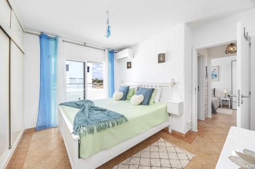 a white bedroom with a large bed with blue pillows at Algarve Sol Beach House in Quarteira
