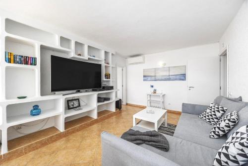 a living room with a gray couch and a flat screen tv at Algarve Sol Beach House in Quarteira