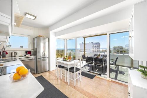 a kitchen and dining room with a large window at Algarve Sol Beach House in Quarteira