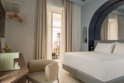 a bedroom with a bed and a chair and a window at Palazzo Tasso in Sorrento