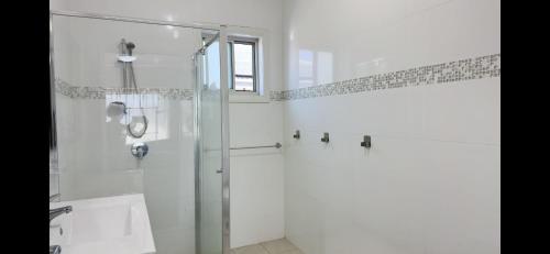 a bathroom with a shower and a glass shower stall at Golf Course Frontage House in Schofields