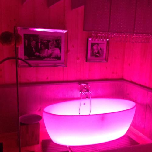 a white tub in a room with red lights at Cabanes flottantes et gîtes au fil de l'eau in Colleville