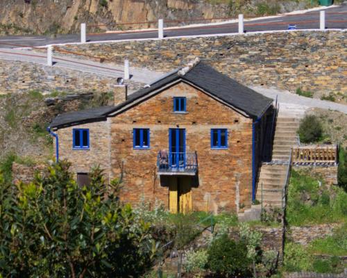 a brick house with blue windows and a balcony at Casa do Padrinho in Teixeira de Baixo