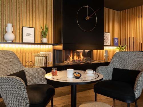 ein Kamin in einem Zimmer mit Tisch und Stühlen in der Unterkunft Mercure Luxembourg Off Kirchberg in Luxemburg (Stadt)