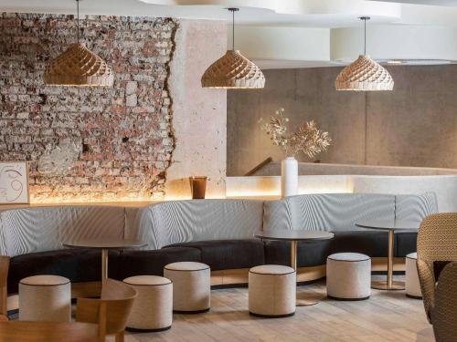 ein Restaurant mit Tischen und Hockern und einer Backsteinmauer in der Unterkunft Mercure Luxembourg Off Kirchberg in Luxemburg (Stadt)